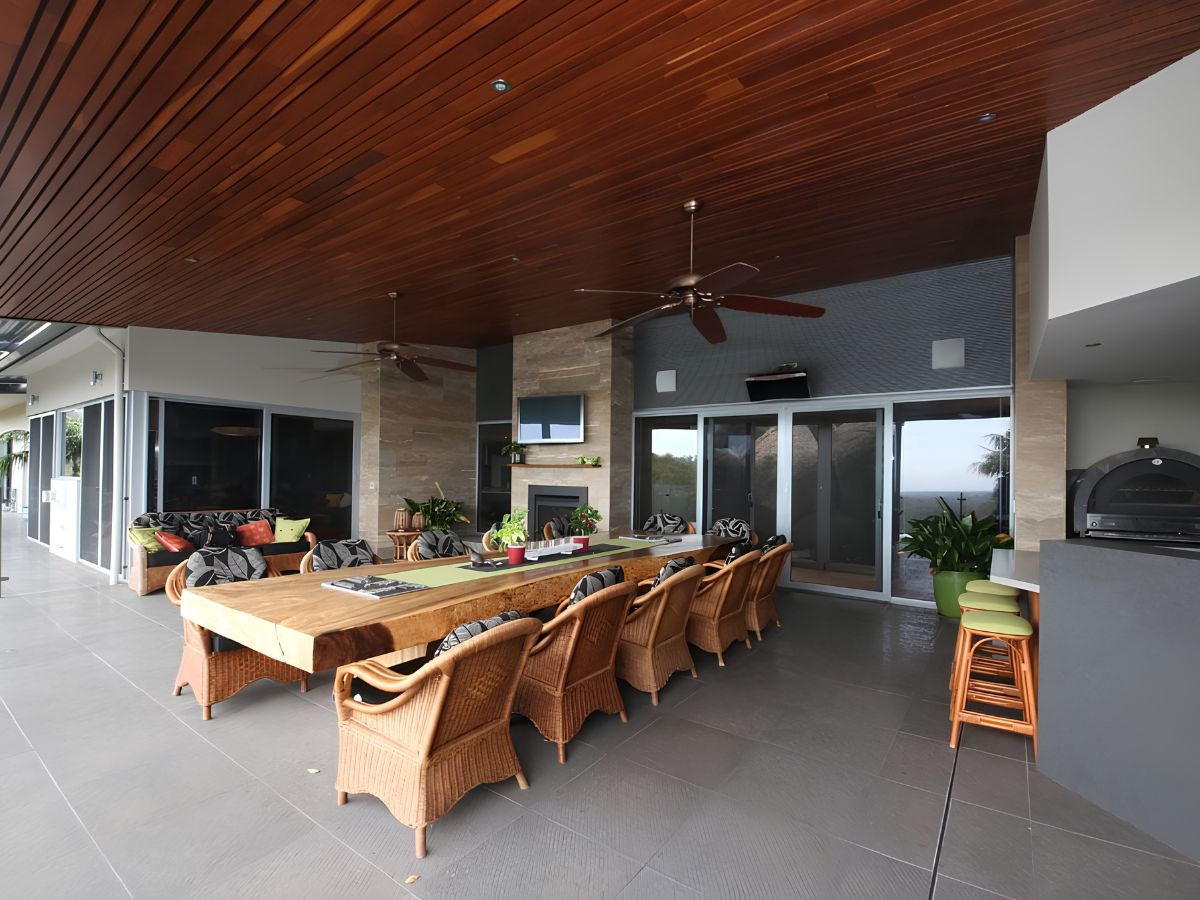 Covered outdoor entertaining area with dining table, ceiling fans and large sliding security doors.
