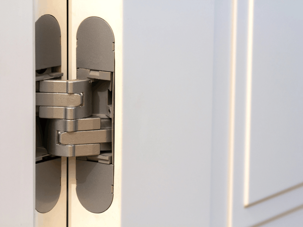 Close-up of a concealed hinge on a white security door