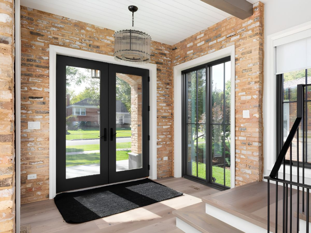 Black-framed French doors and adjacent windows in a brick entryway with natural light.