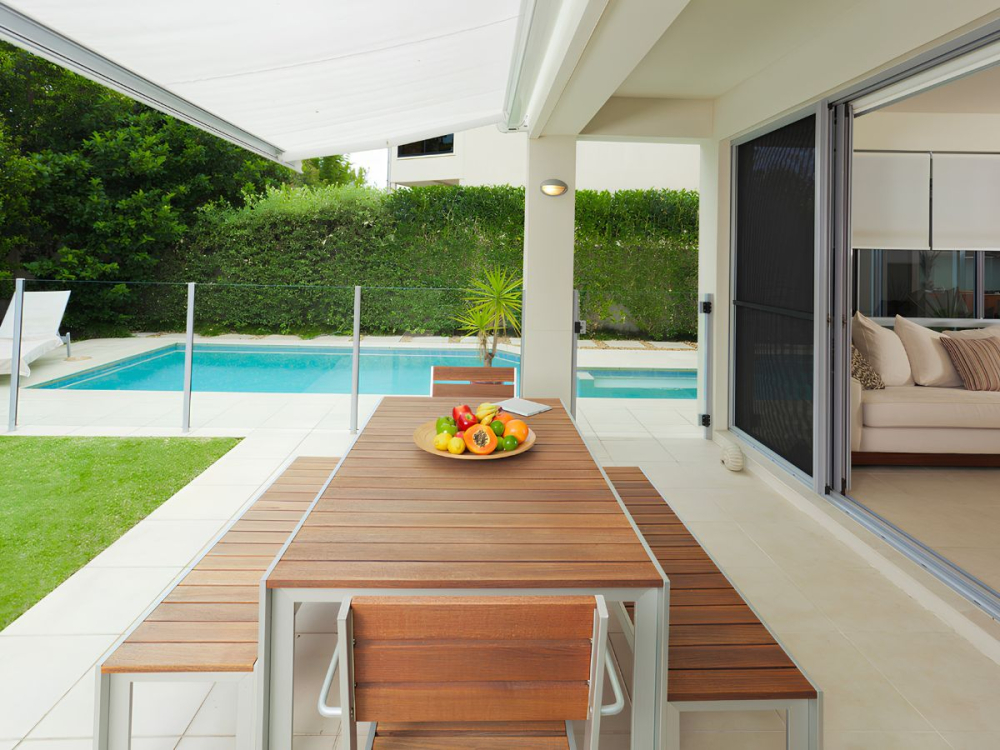 Backyard patio beside a swimming pool with outdoor dining setting and sliding security screen door.