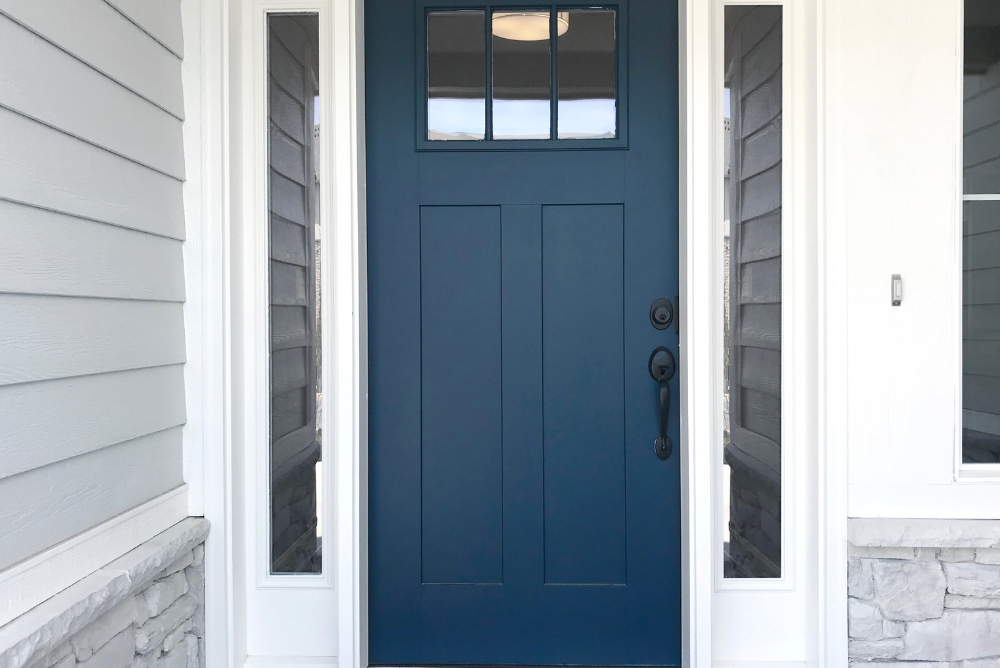 Blue front door with glass side panels at a residential entrance.