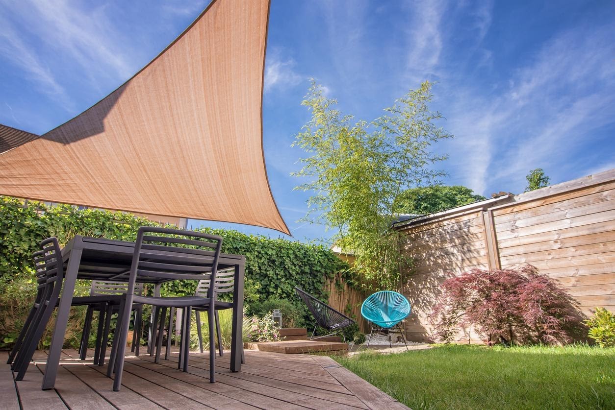 garden with a table and chairs and shade sail